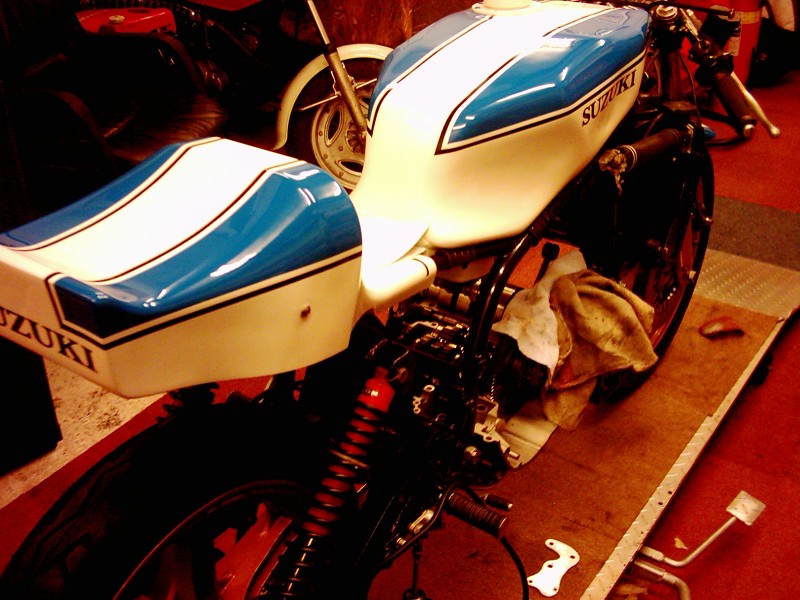 Suzuki TR 750 Marcel Ankone
Hier noch ein Bild von der anderen Seite, interessant dabei der Sitz der 1974er Ausführung mit dem starken "Hüftknick" der eigentlich nicht auf diesen Rahmen gehört! Marcel sagte mir aber, daß er eigentlich nur den Rahmen, die Schwinge, den Tank und einige Kleinteile bekommen habe. Alles anderen Teile wurden von der Vorgängermaschine übernommen, dies erklärt auch den 5-Gang Motor und die alte Verkleidungsform auf den Daytonafotos von 1975. John hat sich den Stand von Mitte der Saison 1975 für seine Restaurierung vorgenommen, das wird schon werden!
