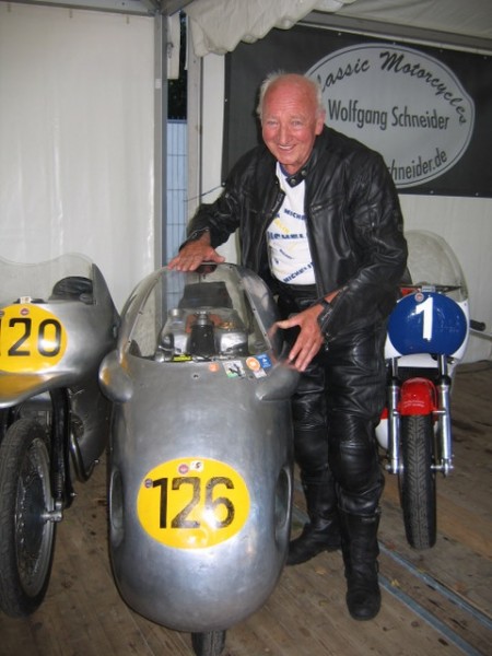 Hamburger Stadtparkrennen 2007
NSU Werksfahrer von 1952/53 Wolfgang Brand strahlt,weil ihn diese Sportmax 2007 bei vielen Demoläufen nie im Stich gelassen hat.Genau wie seine eigene,mit der er 1955 ohne nennenswerte Defekte gefahren ist.Nur einmal verlor er den sicheren Sieg in Ostdeutschland wegen eines Wackelkontakt im Killschalter,schob aber die Max noch für einen Podiumsplatz über das Ziel.Ähnliches war ihm Ende der 40er im Hamburger Stadtpark passiert,nachdem seine selbst getunte alte Vorkriegs NSU ohne Vorderbremse nach einer sicheren Führung den Siegerkranz verwehrte,aber Brand dennmoch auf´s Podium kam.Rechts mit der Nummer 1 die Yamaha TZ 350 unseres Doppelweltmeisters Dieter Braun.Links mit der 120 die Rennmax des 3 fachen Weltmeisters Werner Haas aus Augstburg ,der leider mit einem Sport-Flugzeug abstürzte und verstarb.
